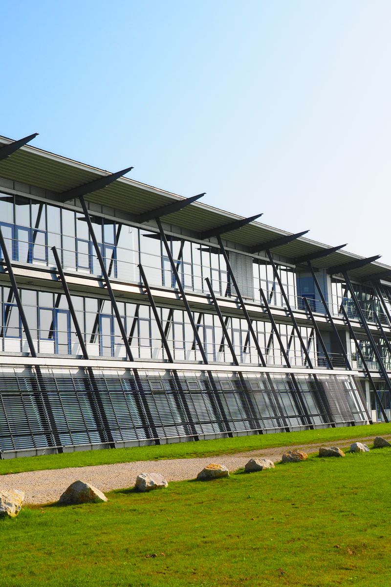Sleek modern architecture with a glass facade and green lawn surroundings.